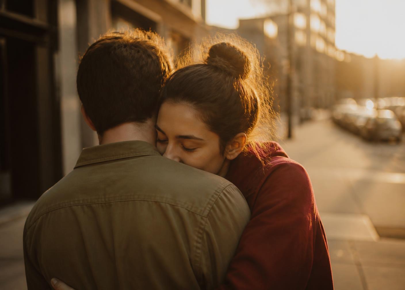 A couple holding each other closely on a city street at golden hour